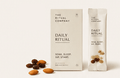 A box and stick pack labeled Daily Ritual from My Store, surrounded by Mamra almonds, chia seeds, and other small round supplements on a white background—perfect for elevating your morning ritual.